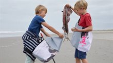 Twee kinderen verzamelen afval op het strand